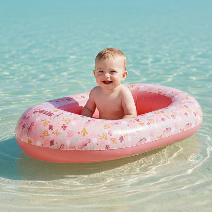 Kind im rosa Ocean Dreams Schlauchboot von Little Dutch im Wasser