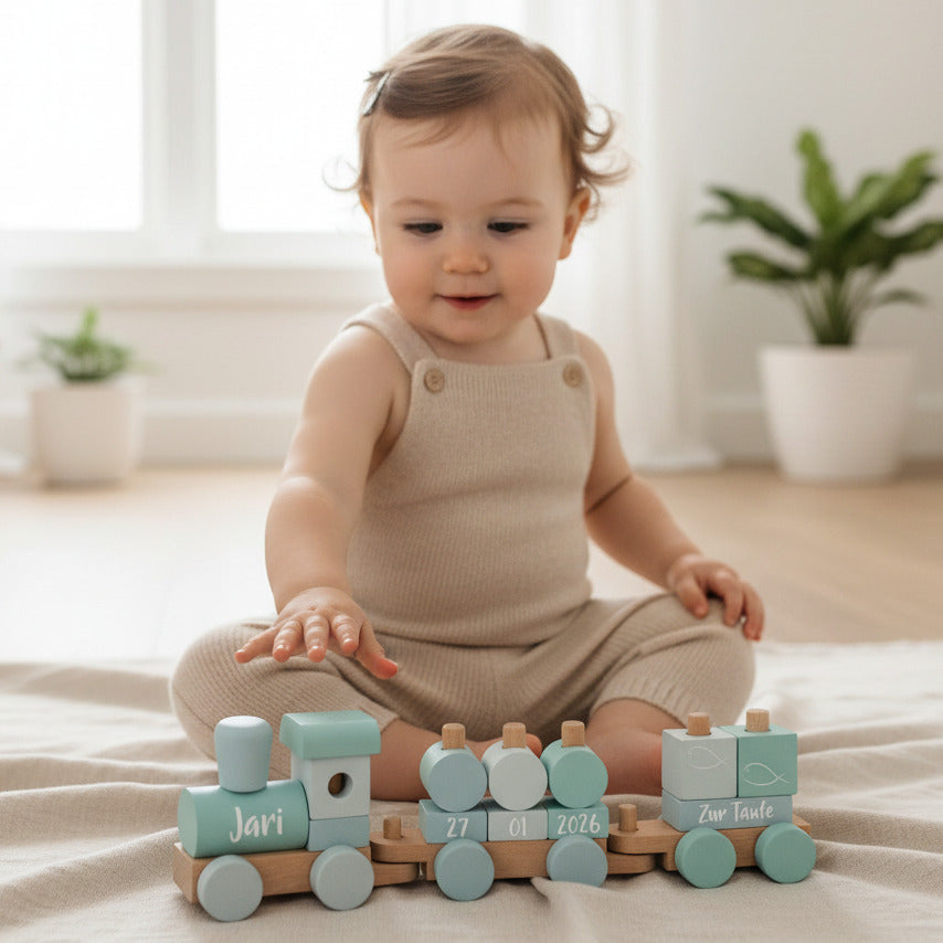 Baby spielt mit personalisiertem Holzzug zur Taufe mit Name und Datum – liebevolles und hochwertiges Taufgeschenk von Schmatzepuffer
