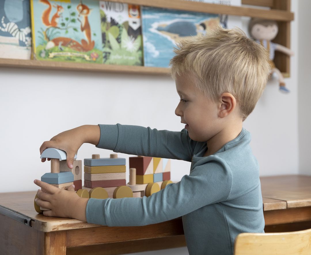 Kind spielt mit dem Holzzug Pure & Nature aus Holz und stapelt die Bausteine auf Lok und Waggons