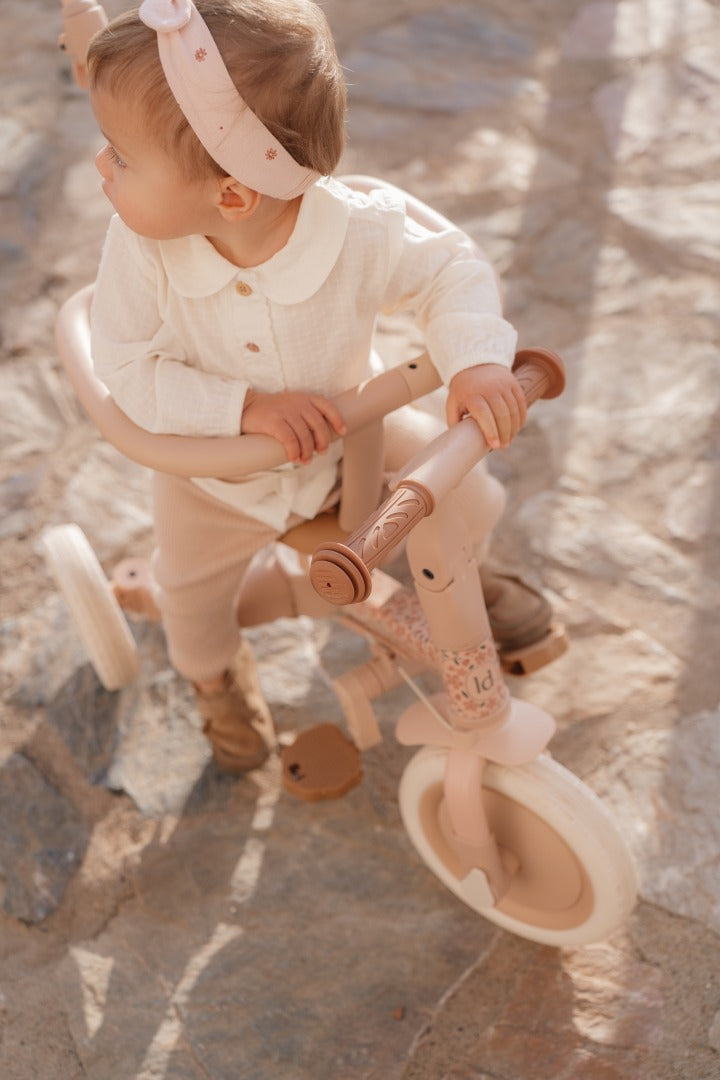 Kleinkind auf mitwachsendem 4-in-1 Dreirad Fairy Floral Rosa beim spielerischen Entdecken. Hochwertiges Kinderfahrzeug für Kinder ab 1 Jahr mit sicherem Sitz, ergonomischem Lenker und Unterstützung der motorischen Entwicklung, Balance und Koordination.